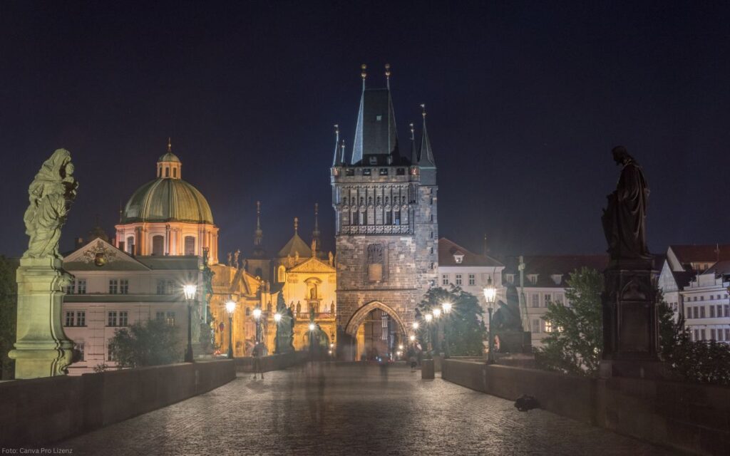 Karlsbrücke bei Nacht mit beleuchtetem Brückenturm und goldenen Reflexionen