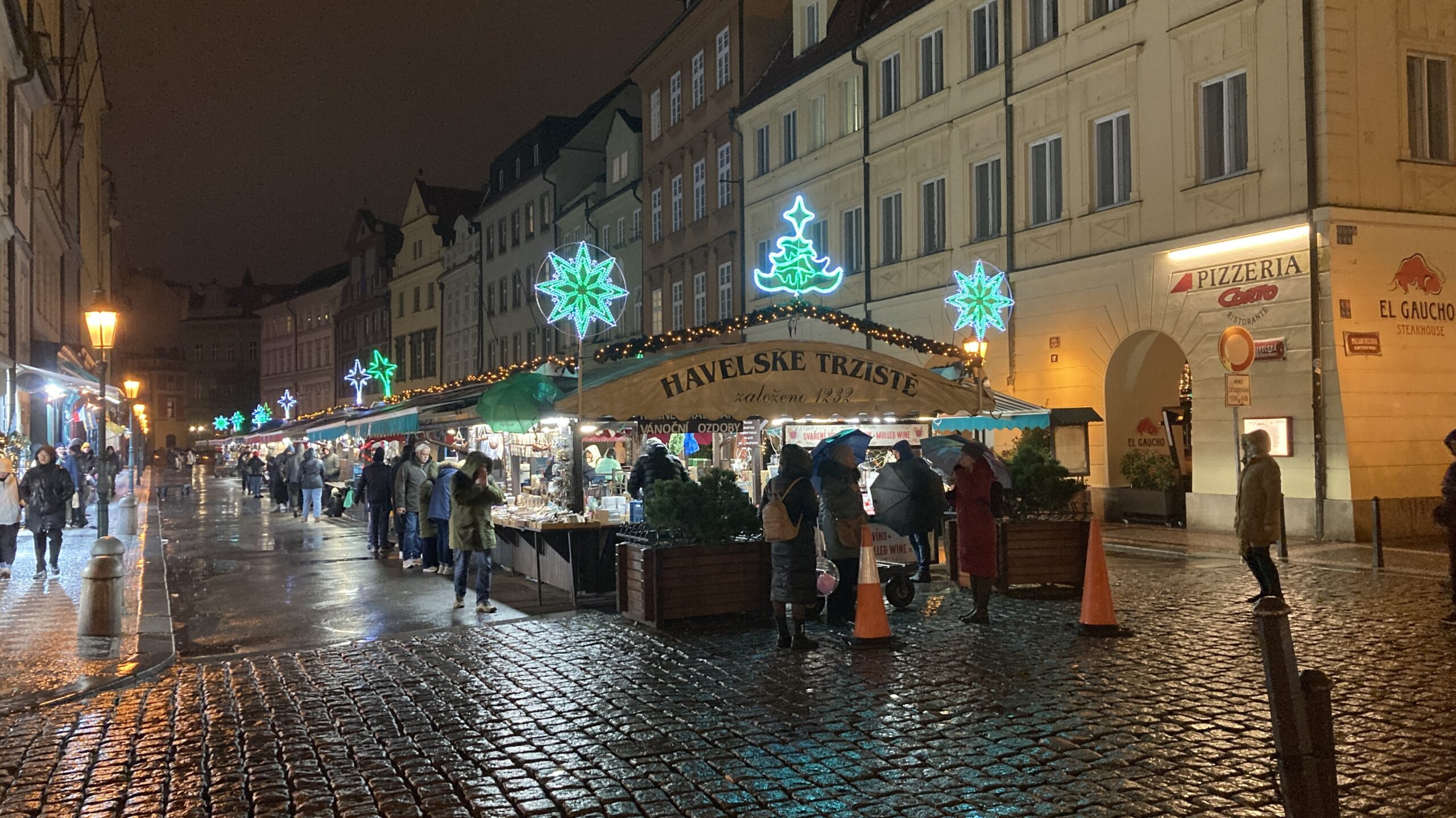 a group of people standing in a street with a tent and lights