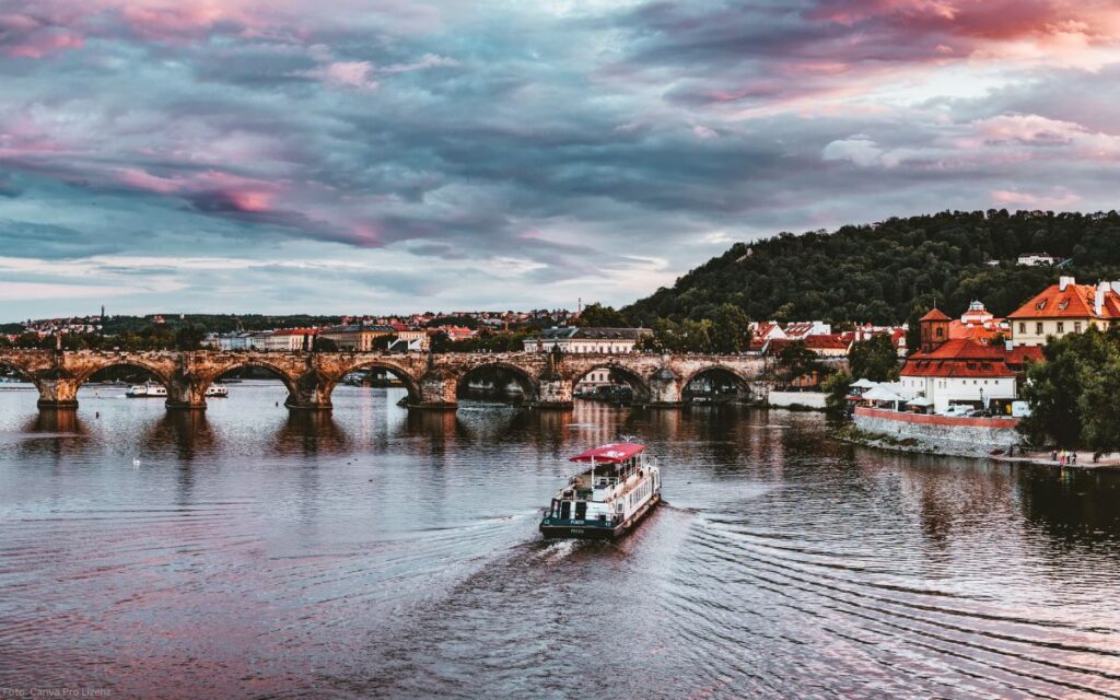 Moldau mit Schiff und Karlsbrücke unter dramatischem Wolkenhimmel