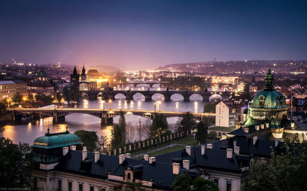 Panorama der Moldau mit mehreren erleuchteten Brücken im Abendhimmel