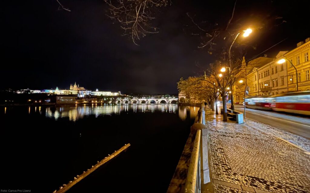 Nachtaufnahme der Moldau mit beleuchteter Karlsbrücke und Uferweg