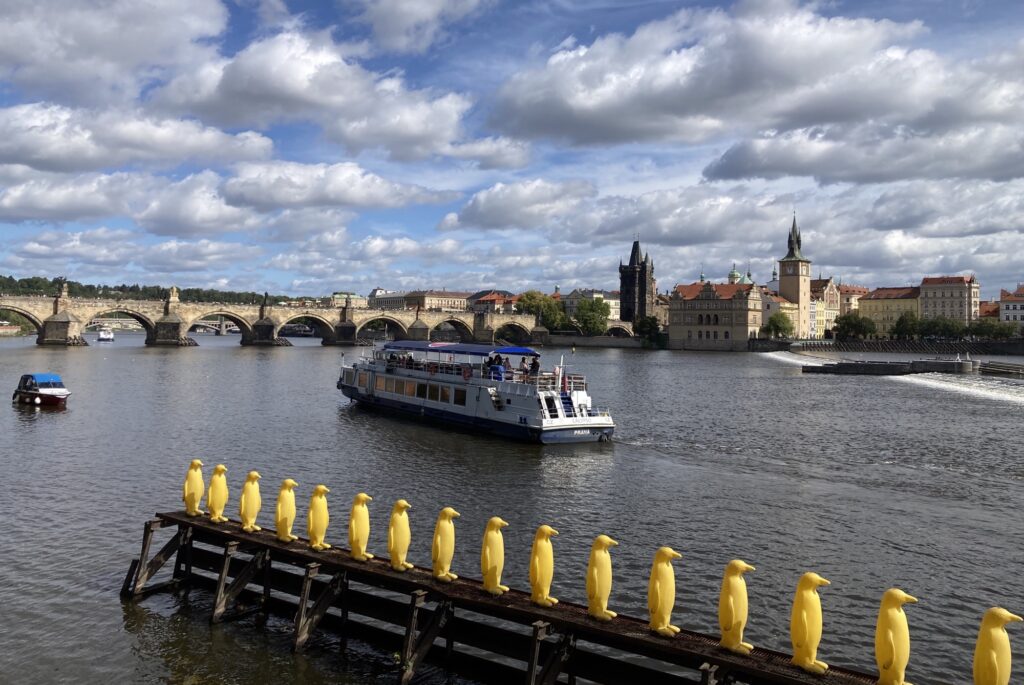 Gelbe Pinguin-Installation am Moldauufer mit Blick auf die Altstadt