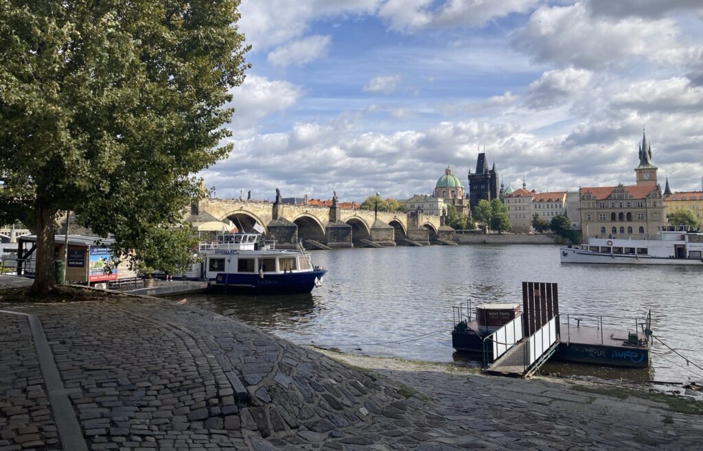 Boot auf der Moldau mit Blick auf Prager Altstadt unter leicht bewölktem Himmel