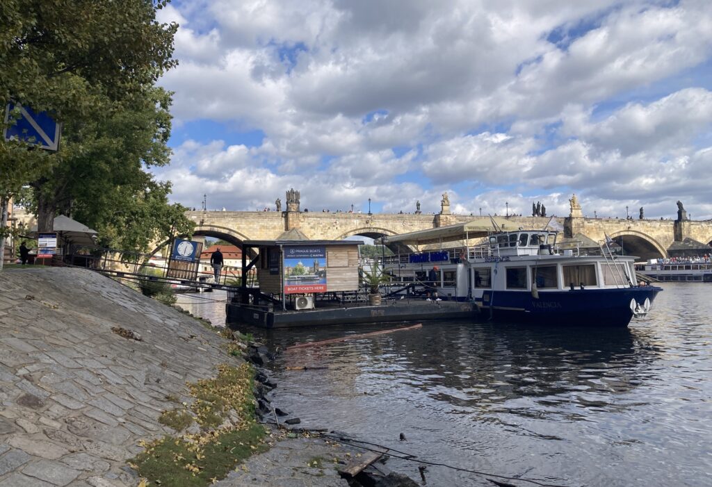 Boote und Anleger an der Moldau unter leicht bewölktem Himmel