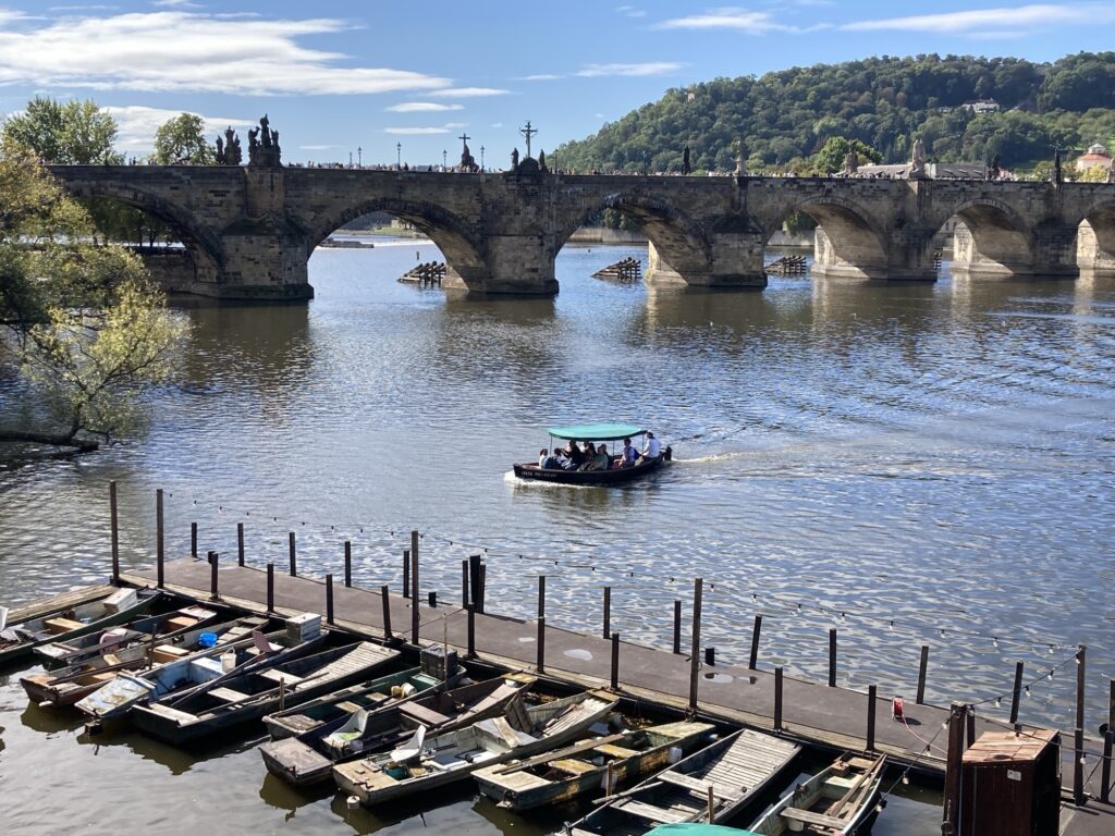 Karlsbrücke vor grünem Hügelpanorama mit Boot und Ufersteg