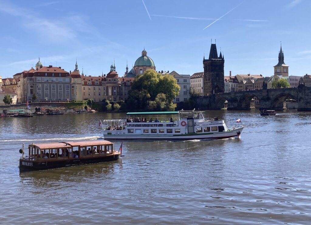 Blick auf die Karlsbrücke und Moldau mit Ausflugsschiff im Sonnenlicht