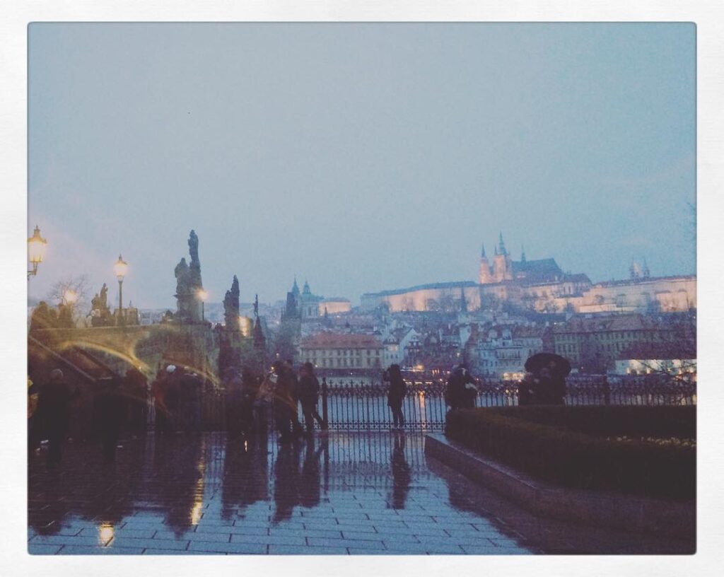 Verregnete Abendstimmung an der Karlsbrücke mit Blick zur Prager Burg. Ein atmosphärischer Moment, der die Mystik der Stadt betont.