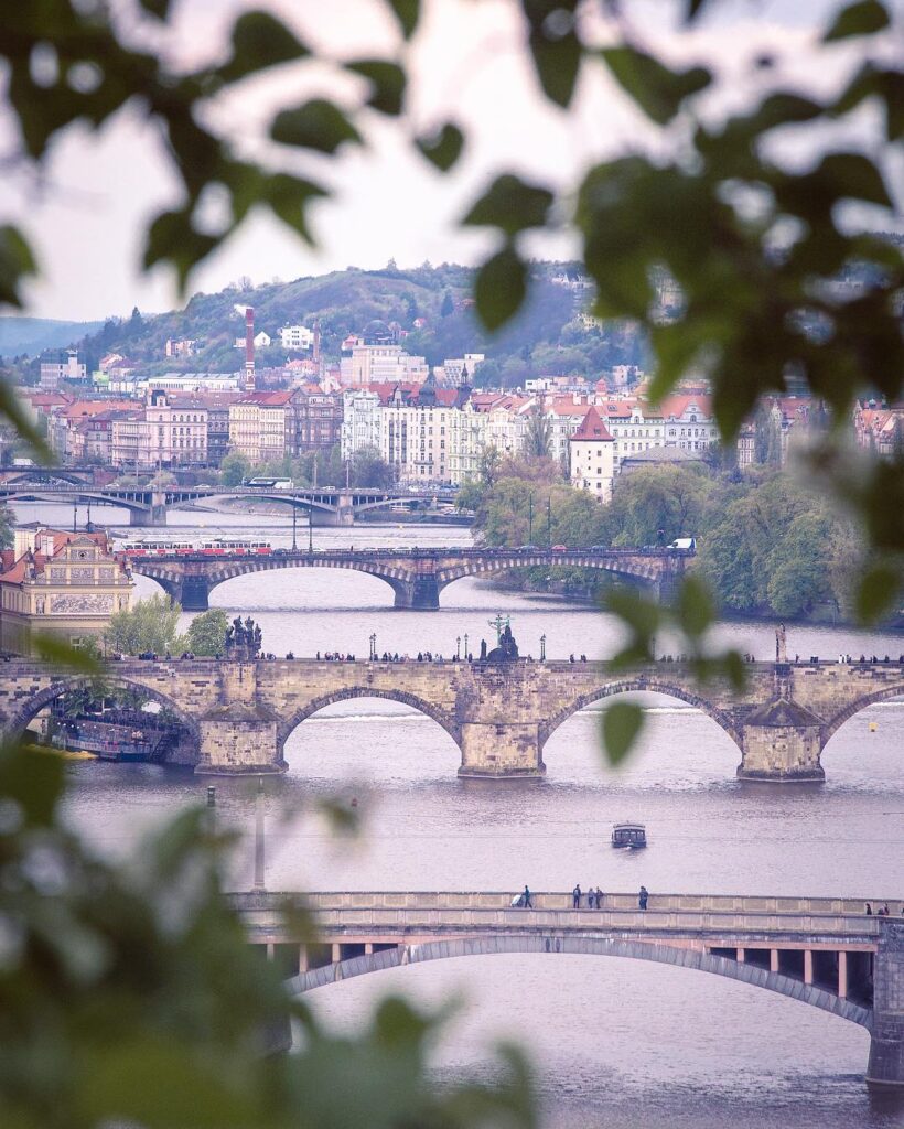 Panoramablick über die Moldau und die historischen Brücken Prags. Weiche Farben und klare Linien zeigen die harmonische Architektur der Stadt.