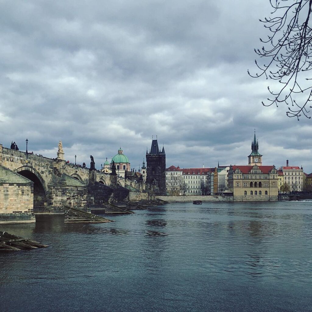 Weitwinkelblick über die Moldau auf Altstadt und Kleinseite unter wolkenverhangenem Himmel. Ein typisches Bild der herbstlichen Prager Stimmung.