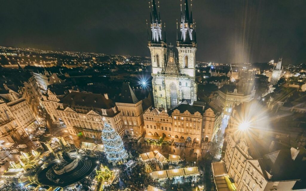 Weihnachtliche Abendansicht des Altstädter Rings in Prag mit beleuchteter Teynkirche und Weihnachtsmarkt aus der Vogelperspektive