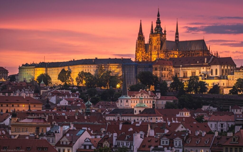 Abendlicher Blick auf die Prager Burg mit Veitsdom über den Dächern der Altstadt bei rosafarbenem Himmel