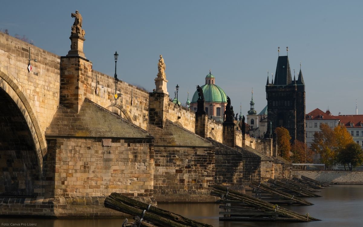 Karlsbrücke in Prag mit barocken Statuen, Brückenbögen und Blick auf den Altstädter Brückenturm entlang der Moldau