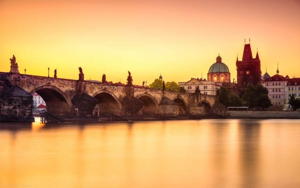 Karlsbrücke in Prag bei Sonnenuntergang mit barocken Statuen, Brückenbögen und ruhiger Moldau