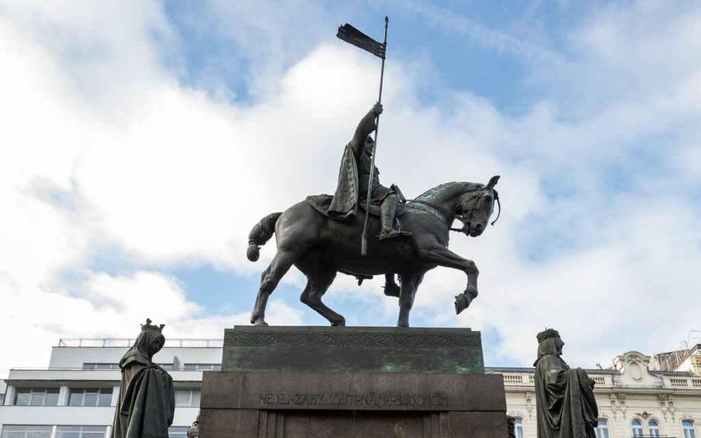 Reiterstandbild des Heiligen Wenzel auf dem Wenzelsplatz in Prag mit erhobener Fahne vor hellem Himmel
