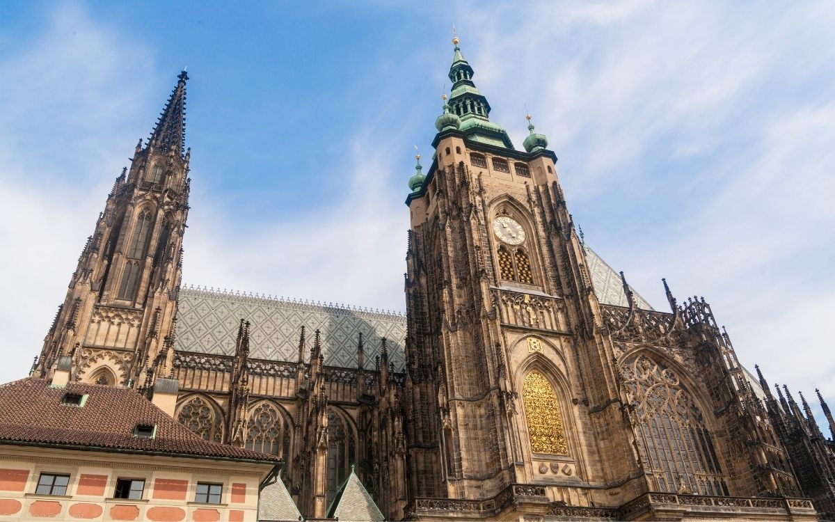 Gotische Türme und Fassade des Veitsdoms auf der Prager Burg vor hellem Himmel