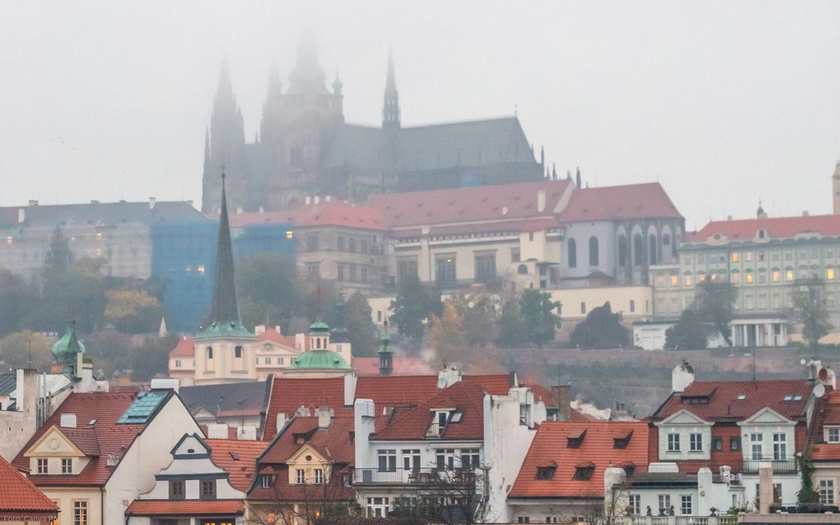 Prager Burg mit Veitsdom im Nebel über den roten Dächern der Kleinseite