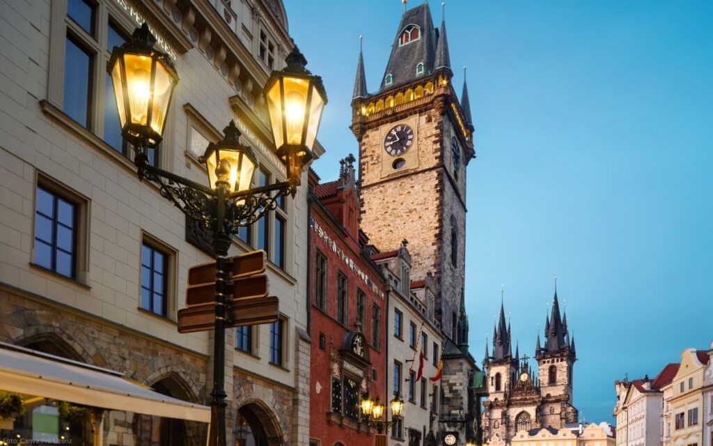 Abendlicher Blick durch die Prager Altstadt mit beleuchteten Laternen und dem Altstädter Brückenturm im Hintergrund