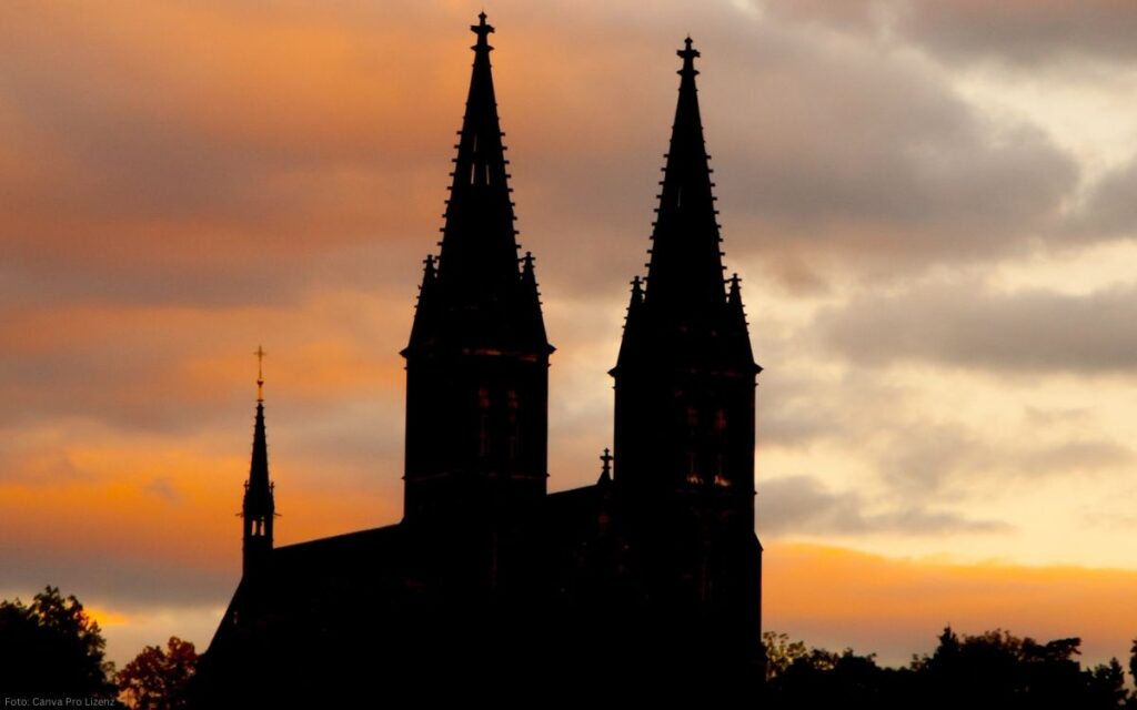 Silhouette der Vyšehrad-Kirche mit zwei Türmen vor farbigem Abendhimmel in Prag