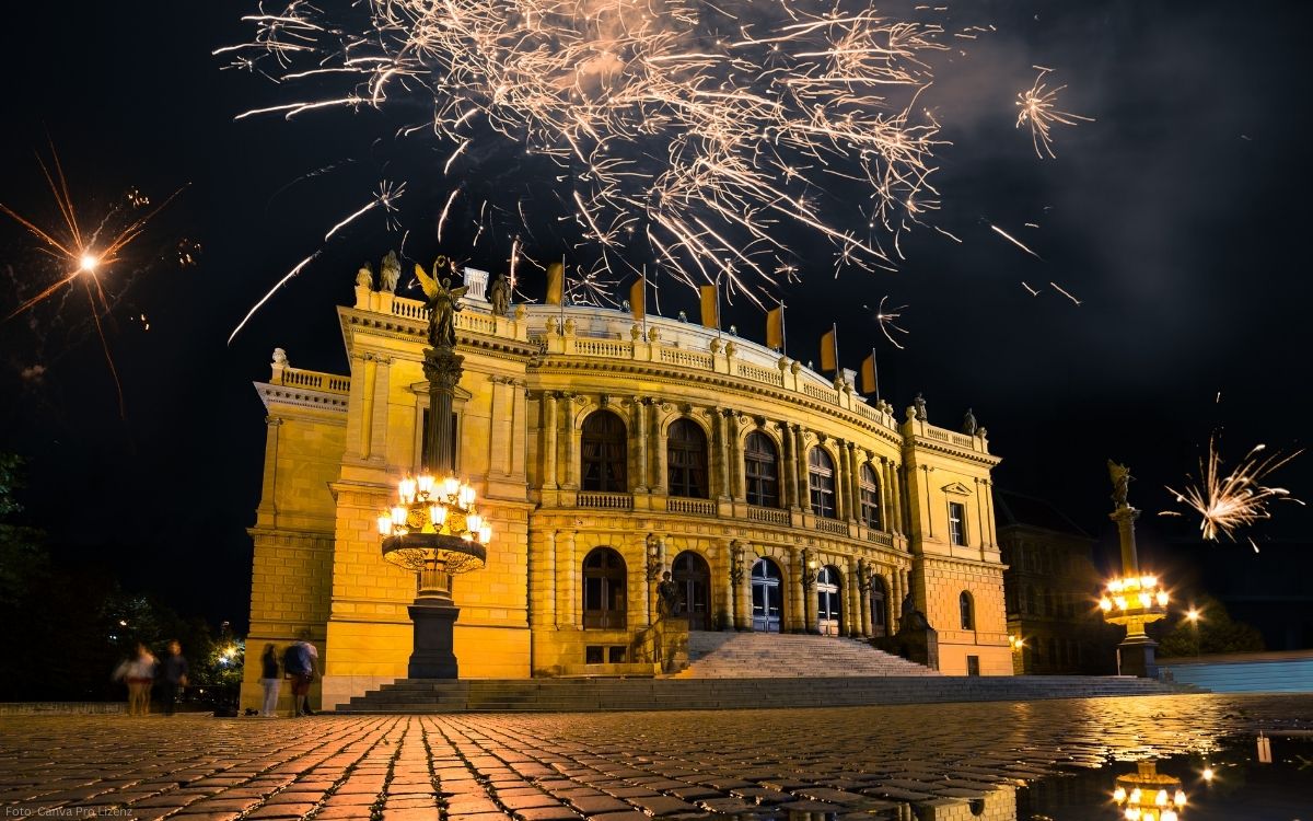 Feuerwerk über dem Rudolfinum in Prag bei Nacht mit beleuchtetem Konzertgebäude und Kopfsteinpflaster im Vordergrund