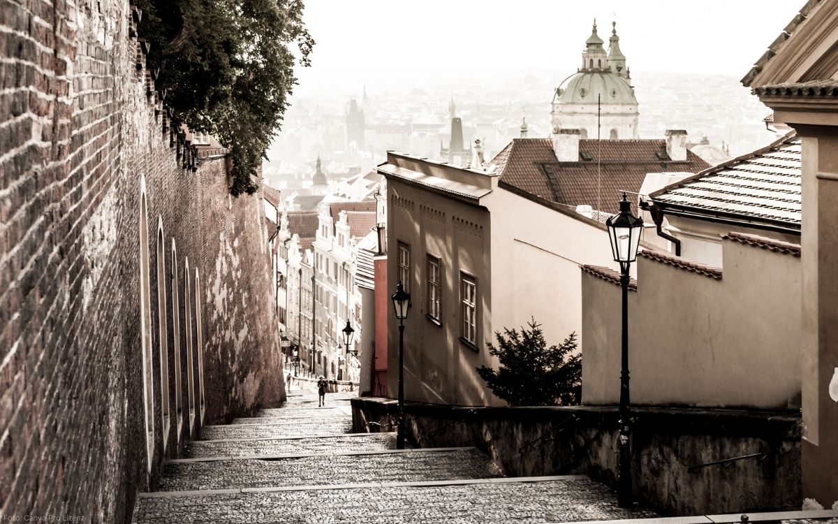 Schlossstiege in Prag mit steilem Kopfsteinpflaster, historischen Häusern und Blick auf die Altstadt