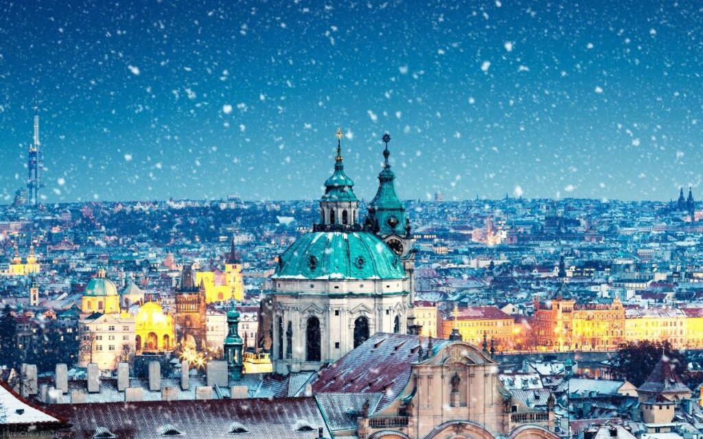 Winterlicher Blick über Prag mit der St.-Nikolaus-Kirche auf der Kleinseite im Schneefall
