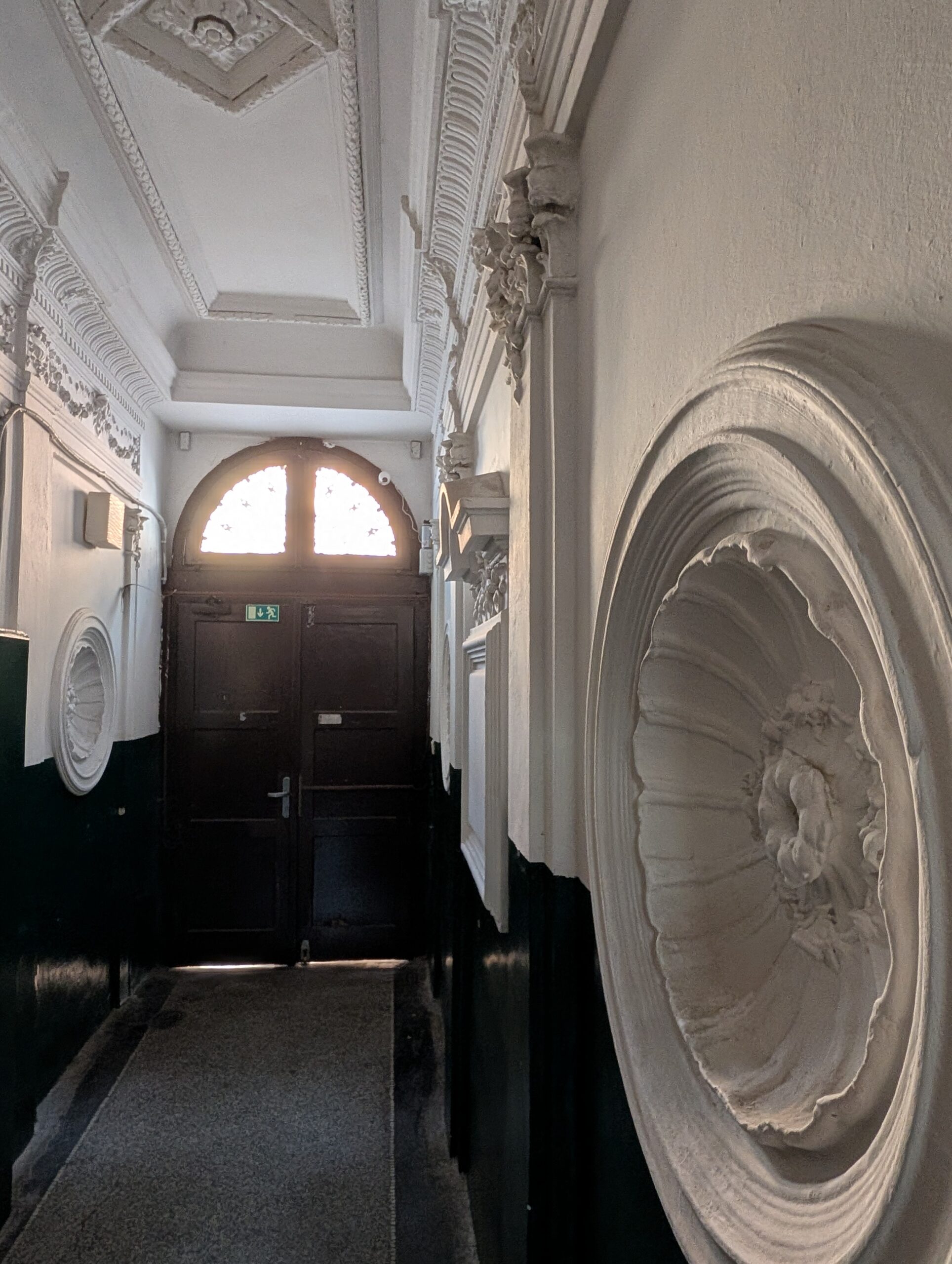 Historischer Eingangsflur in Prag mit Stuckdecke, runden Wandmedaillons und dunkler Holztür