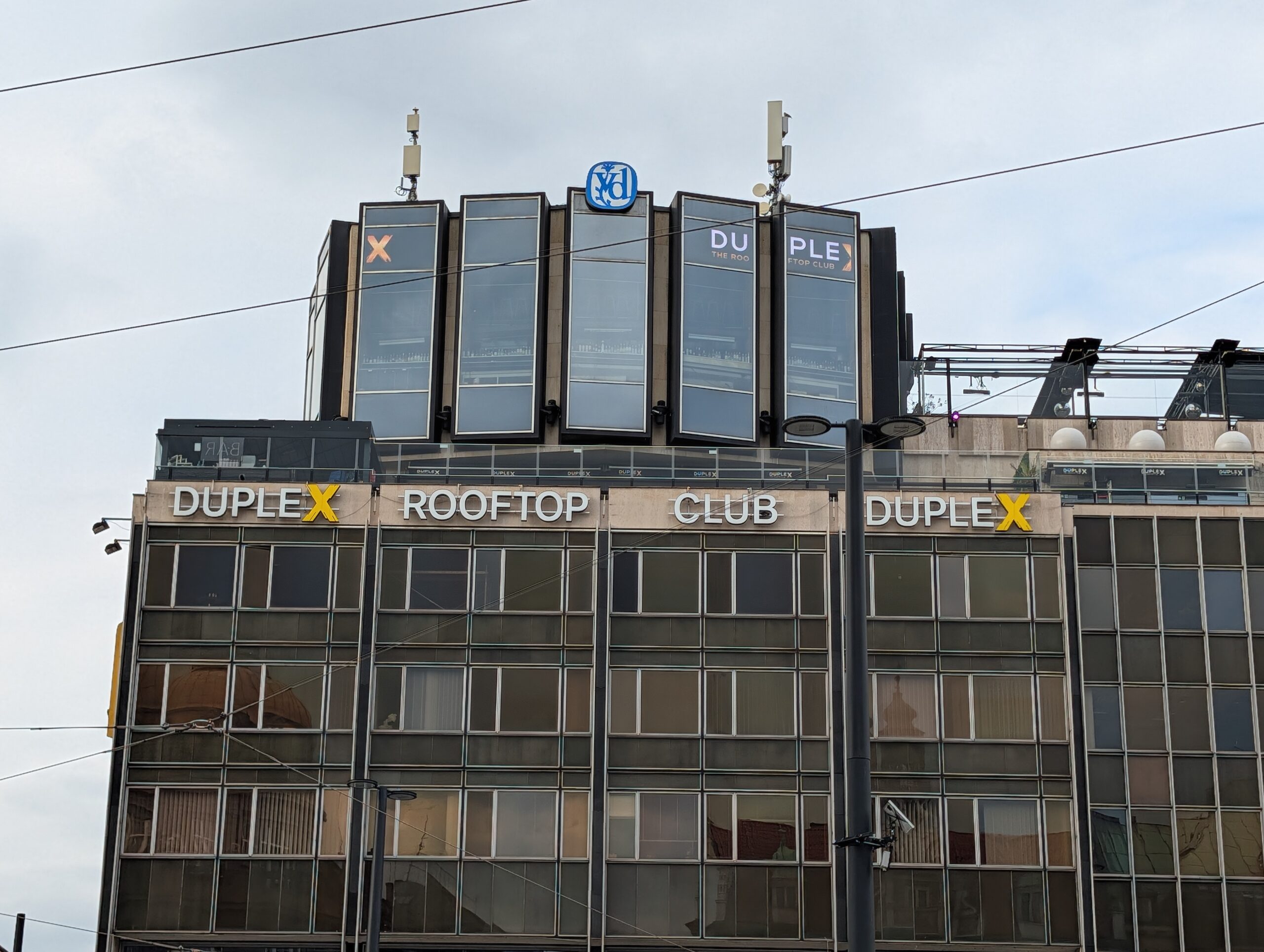 Duplex Rooftop Club am Wenzelsplatz mit moderner Glasfassade, großem Schriftzug und Dachterrasse