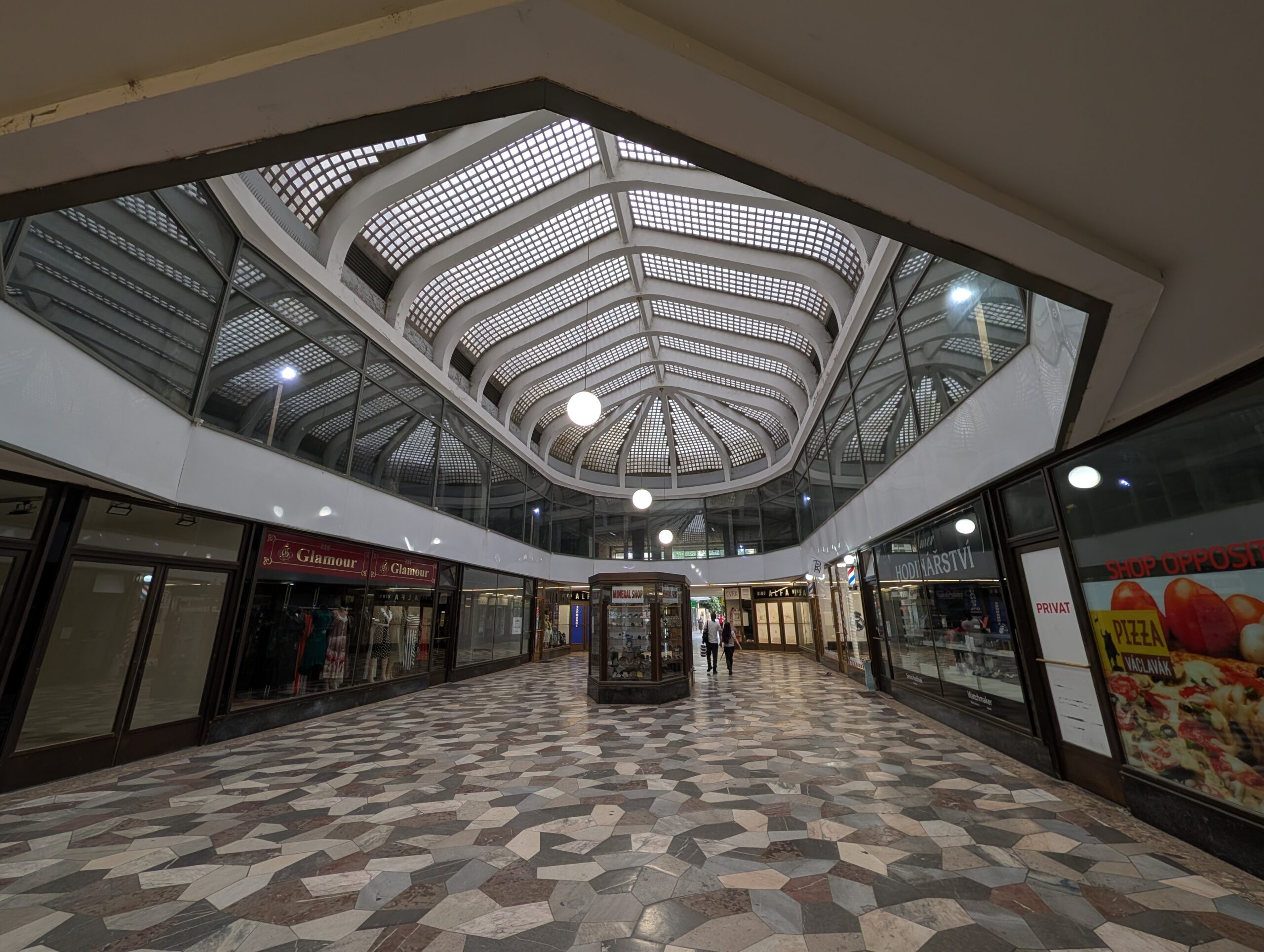 Überdachte Passage im Palast U Stýblů in Prag mit Glasdach, geometrischem Steinboden und Geschäften