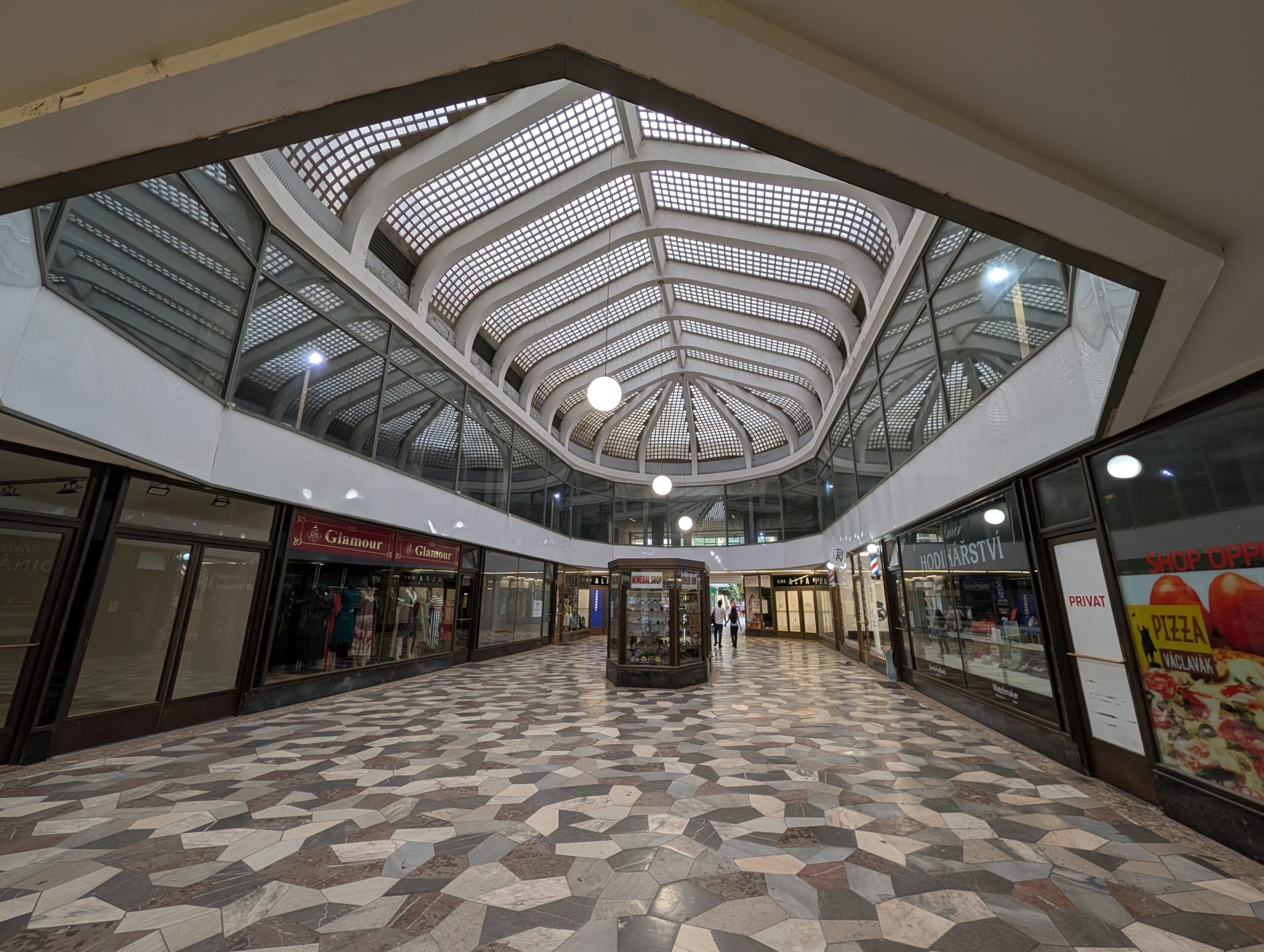 Überdachte Passage im Palast U Stýblů in Prag mit Glasdach, geometrischem Steinboden und Geschäften
