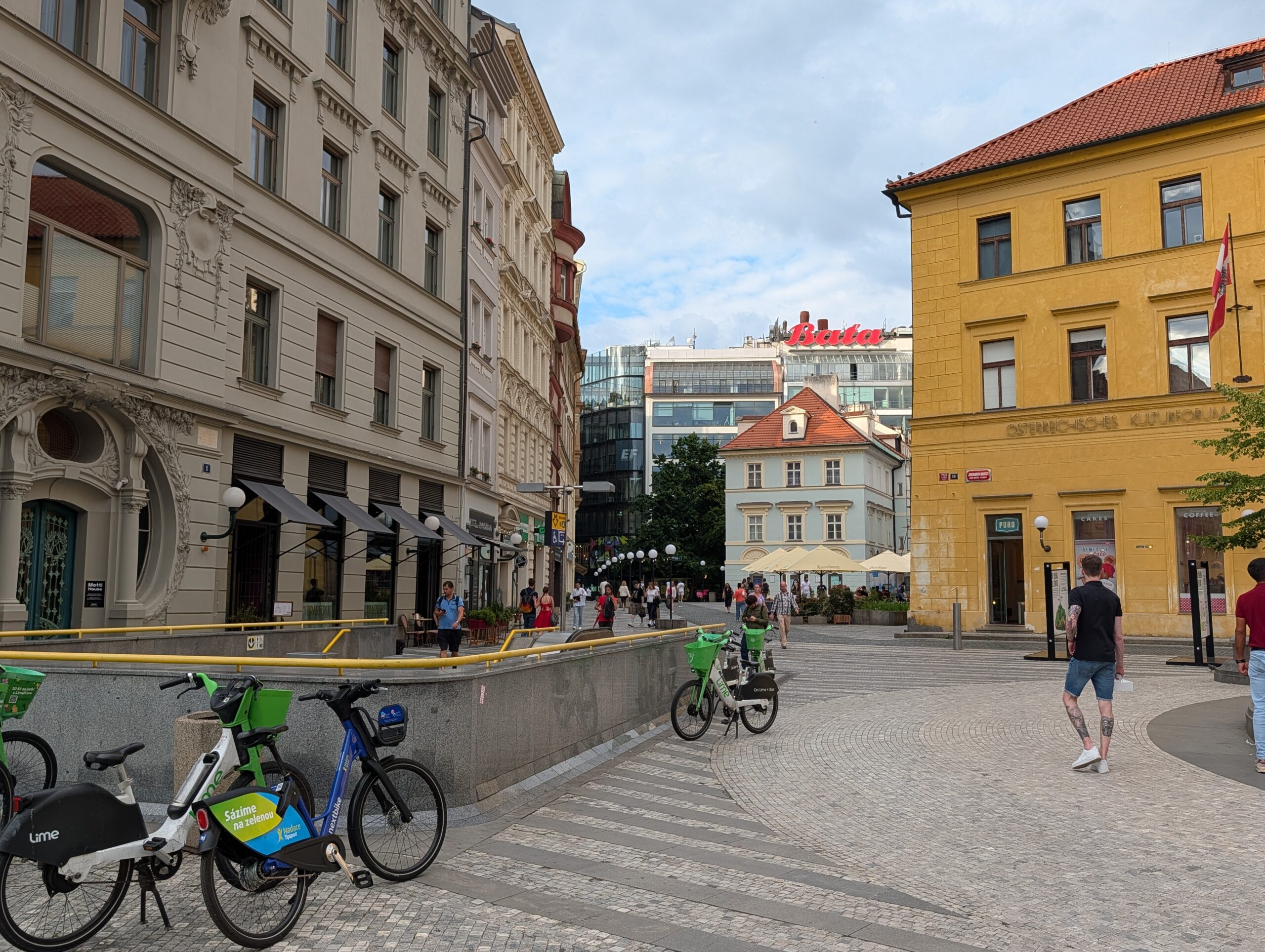 Jungmannplatz in Prag mit historischen Fassaden, Leihfahrrädern, Fußgängern und Blick Richtung Můstek