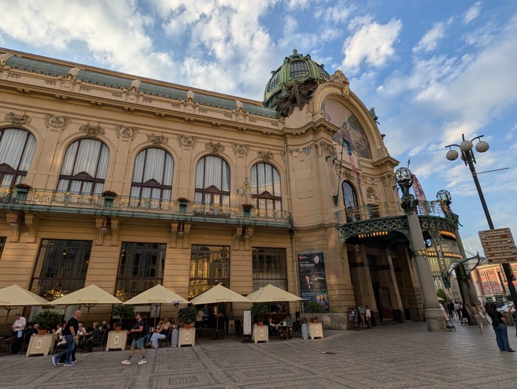 Gemeindehaus in Prag mit Jugendstilfassade, Kuppel, Rundbogenfenstern und Außengastronomie am Platz der Republik