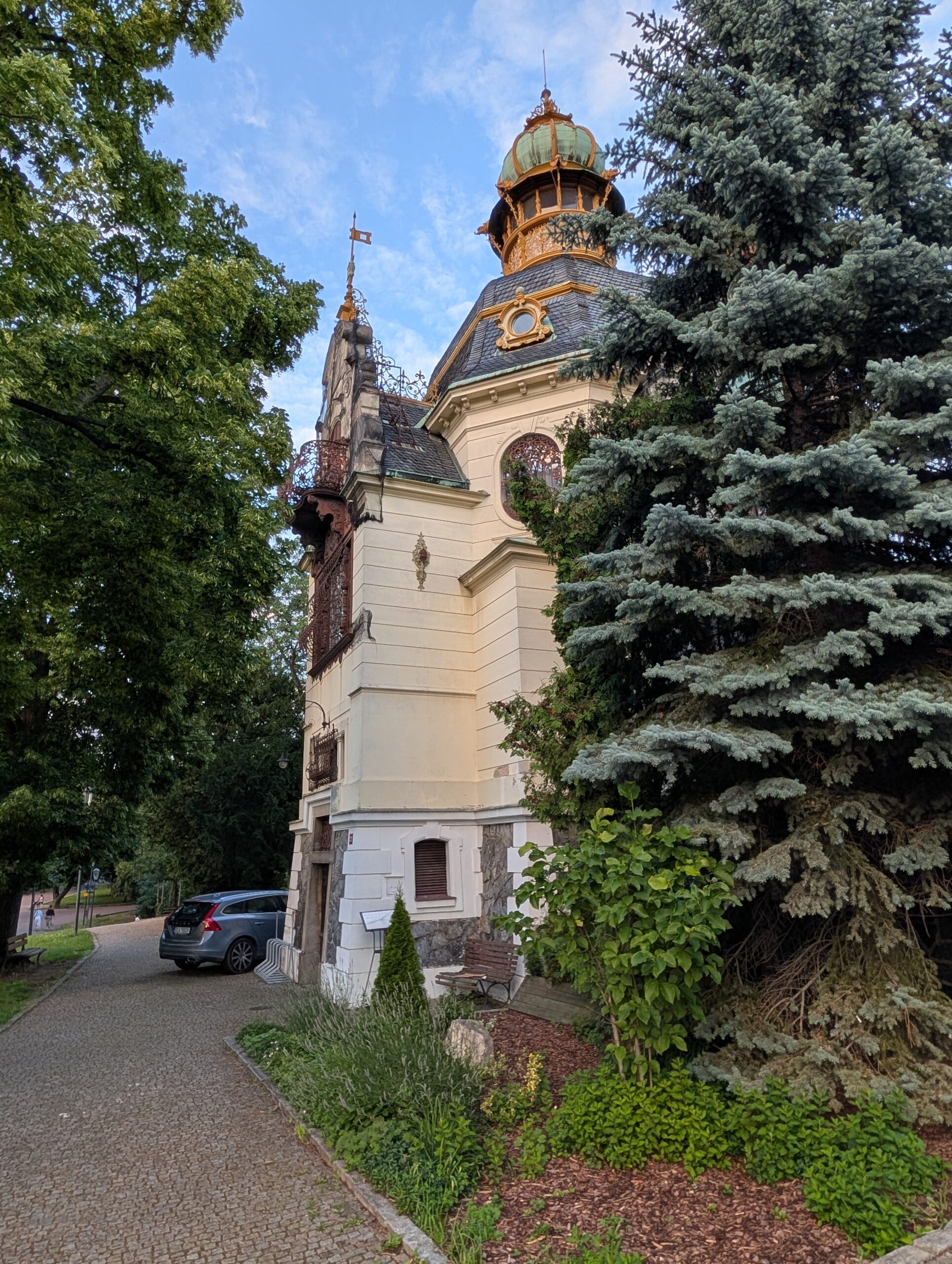 Hanau-Pavillon im Letná-Park mit verziertem Turm, grün patiniertem Dach und dichtem Baumbestand