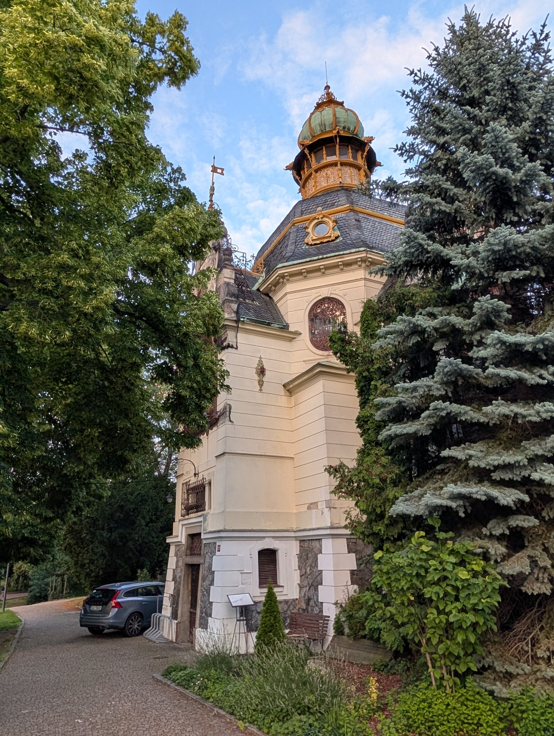 Hanau-Pavillon im Letná-Park mit verziertem Turm, grün patiniertem Dach und dichtem Baumbestand