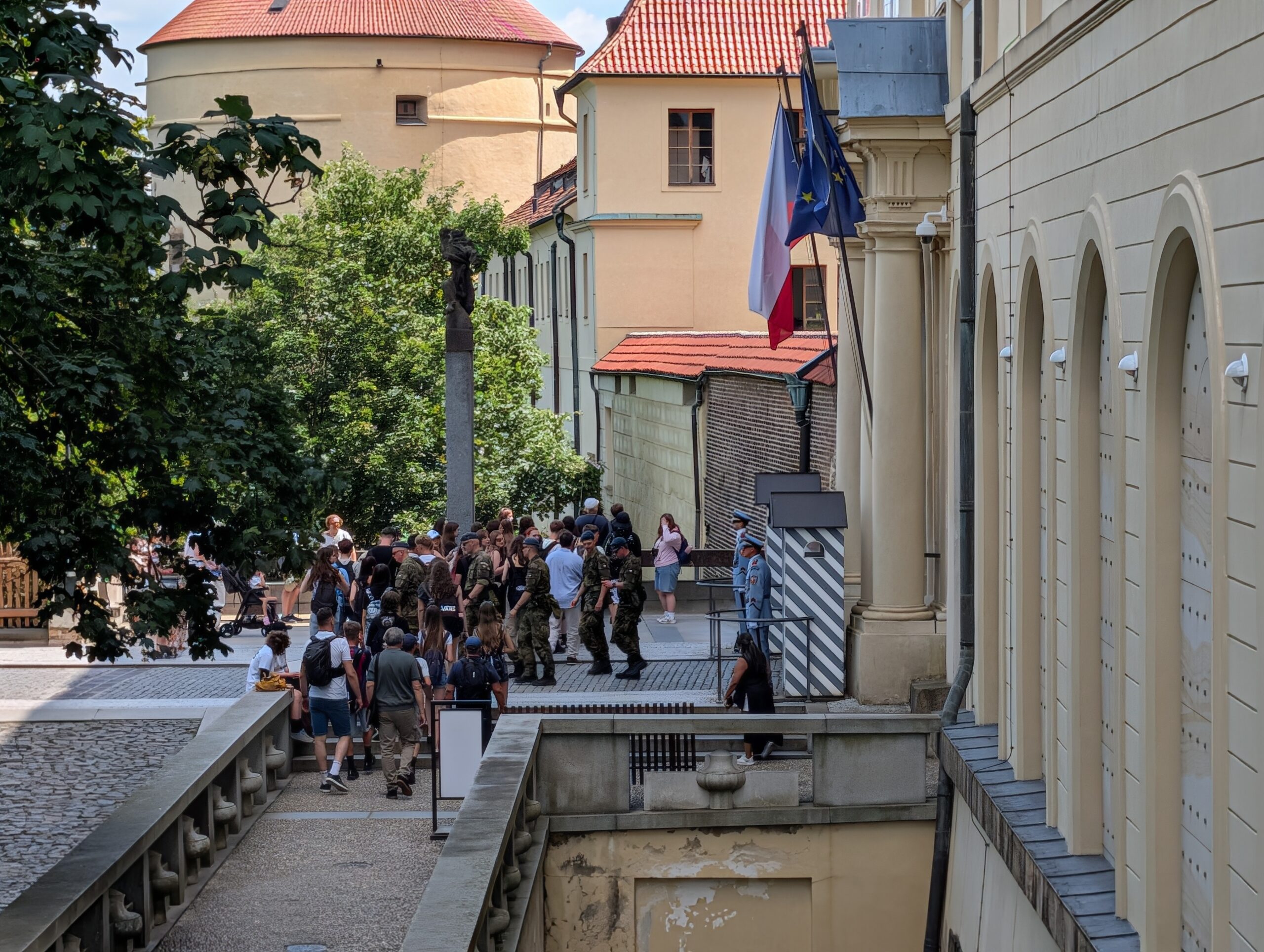 Besucher am kontrollierten Eingang der Prager Burg mit Burgwache, Sicherheitskräften und tschechischer Flagge