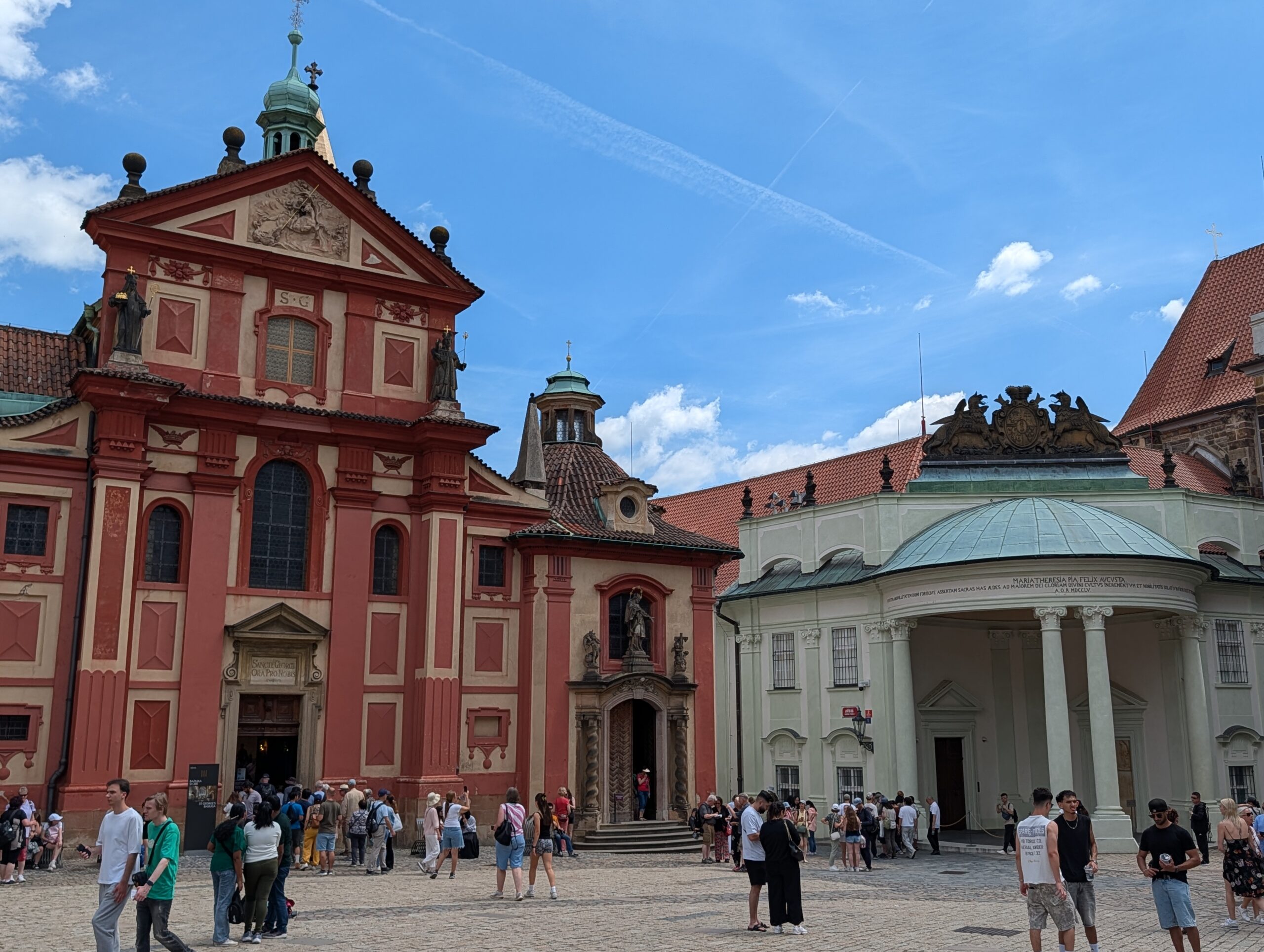 St.-Georgs-Basilika mit roter Barockfassade, hellem Säulenbau und Besuchern auf dem Georgsplatz der Prager Burg
