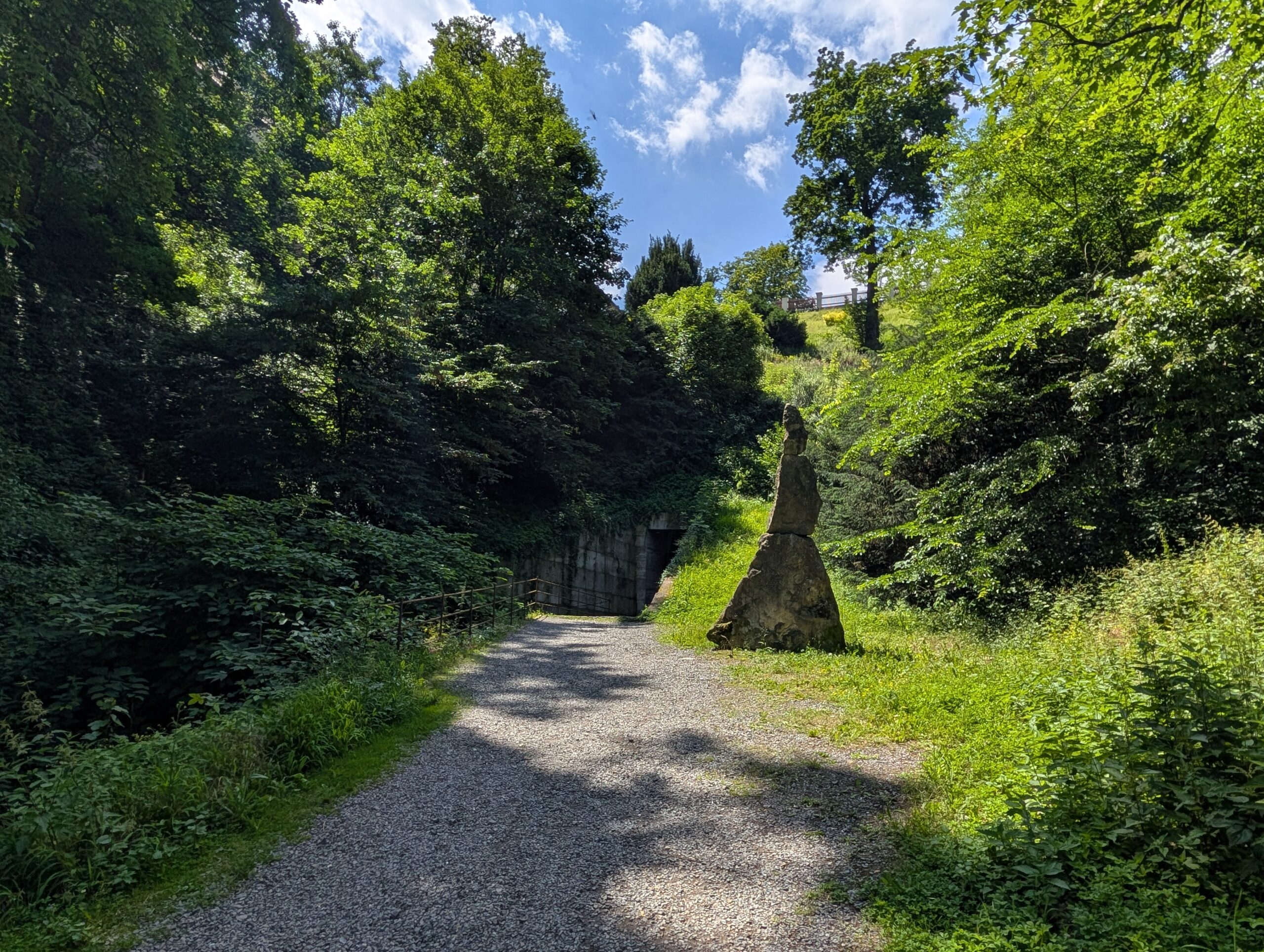 Schmaler Bachlauf zwischen dichter Vegetation und Spazierweg im Hirschgraben unterhalb der Prager Burg