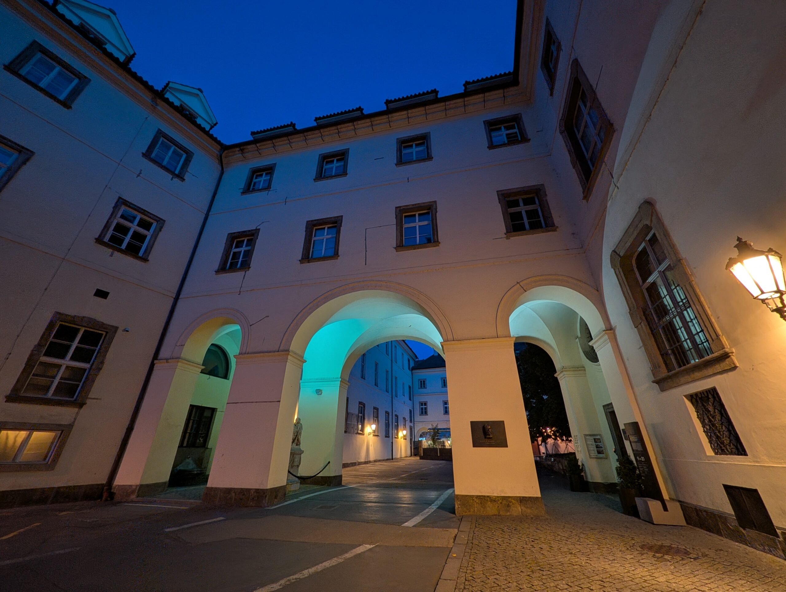Beleuchtete Arkaden und historische Fassaden im Innenhof des Klementinums in Prag bei Nacht
