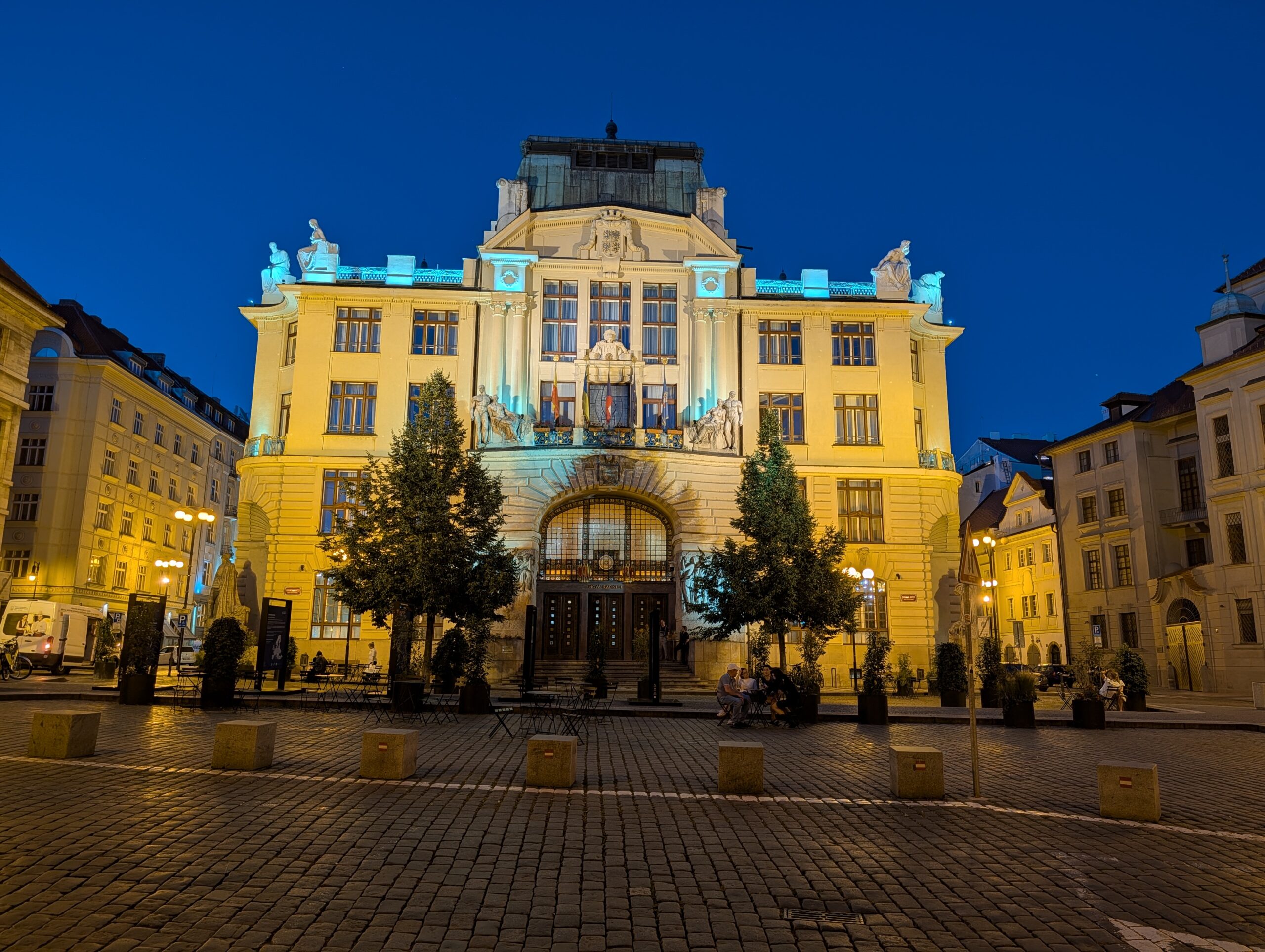 Beleuchtetes Neues Rathaus mit Skulpturen und Rundbogenportal am Marienplatz in Prag bei Nacht