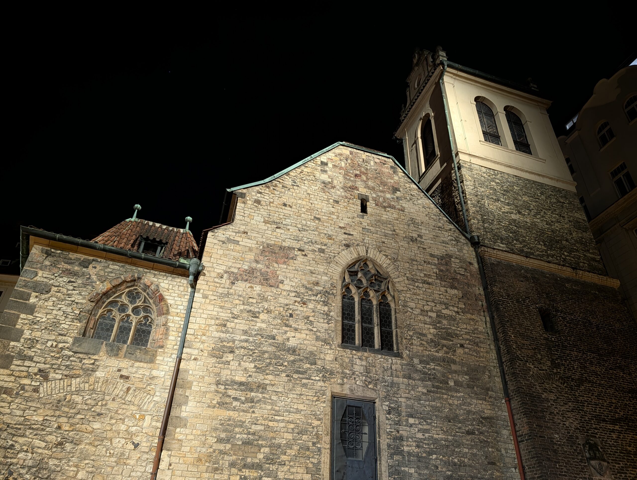Beleuchtete St.-Martin-in-der-Mauer-Kirche mit gotischen Fenstern und Kirchturm in Prag bei Nacht