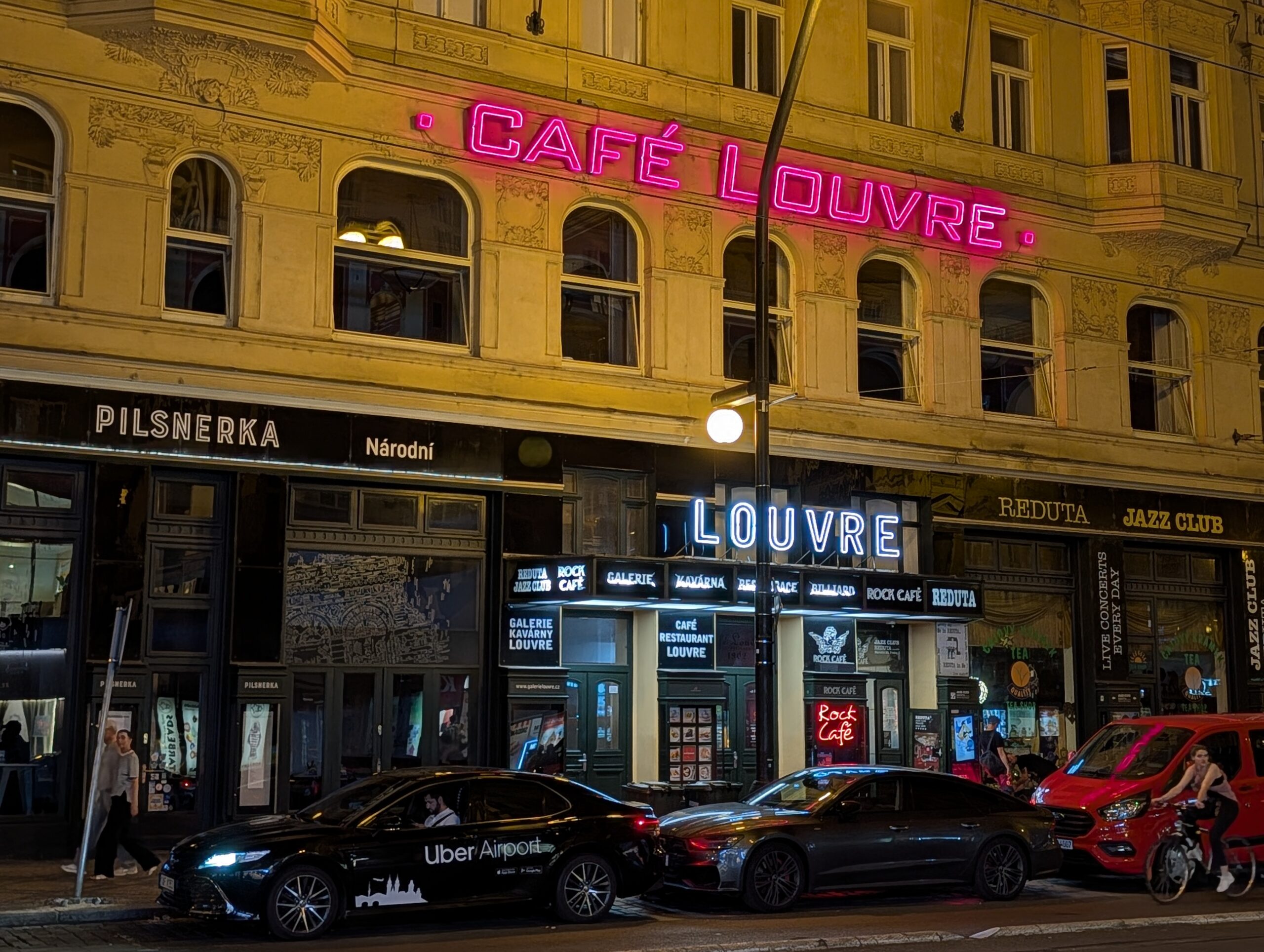 Beleuchtete Fassade des historischen Café Louvre mit auffälliger Neonreklame an der Národní třída bei Nacht in Prag.