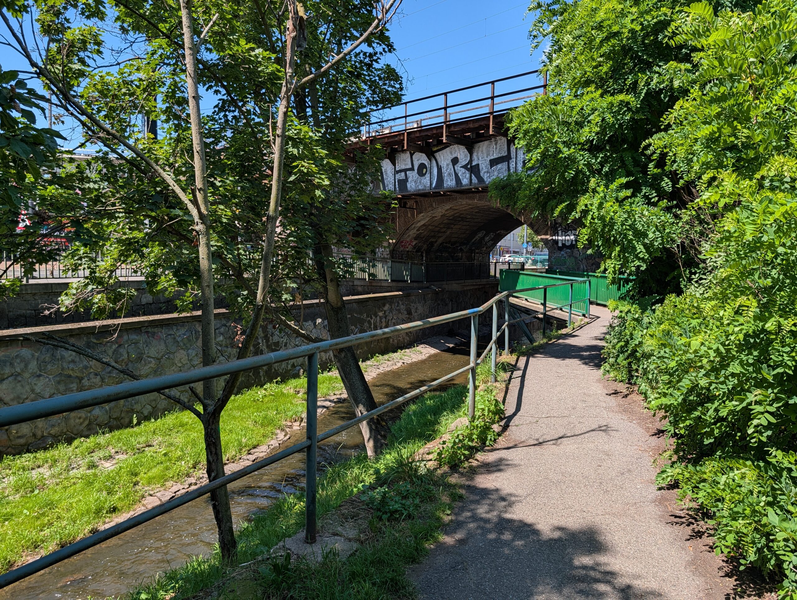 Fußweg am Bach Botič unter der Eisenbahnbrücke bei Fidlovačka in Prag.
