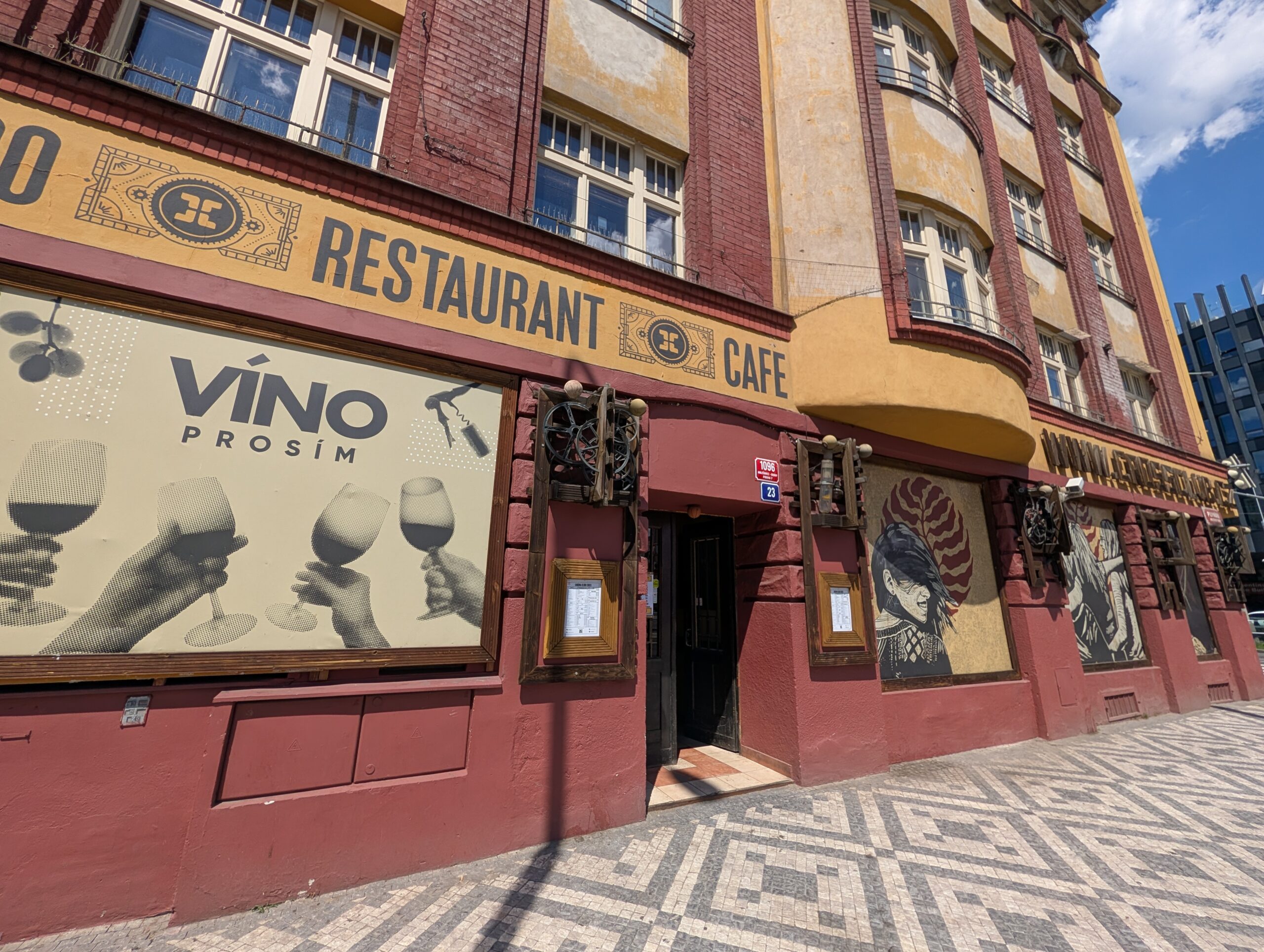 Eingang zum Restaurant und Café des Cross Club in Prag-Holešovice mit dekorativer Fassade und Gehweg vor dem Gebäude.