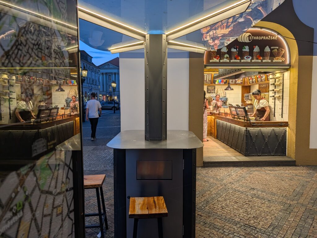 Verkaufsstand für frisch gebackene Baumstriezel in der Prager Altstadt bei Abenddämmerung.