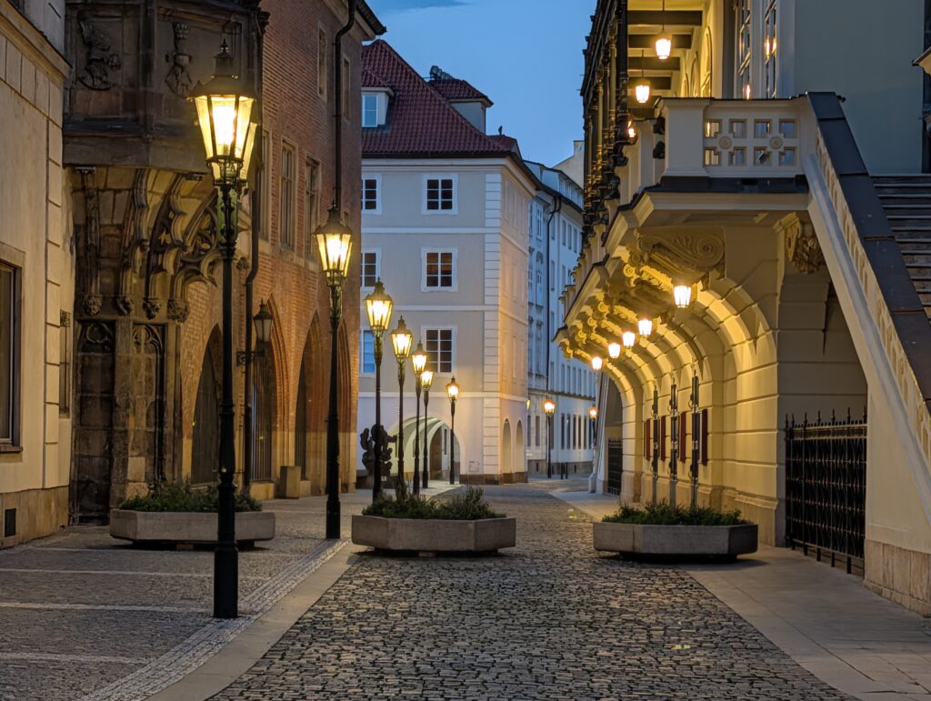 Historische Gasse mit beleuchteten Laternen in der Prager Altstadt bei Abenddämmerung.