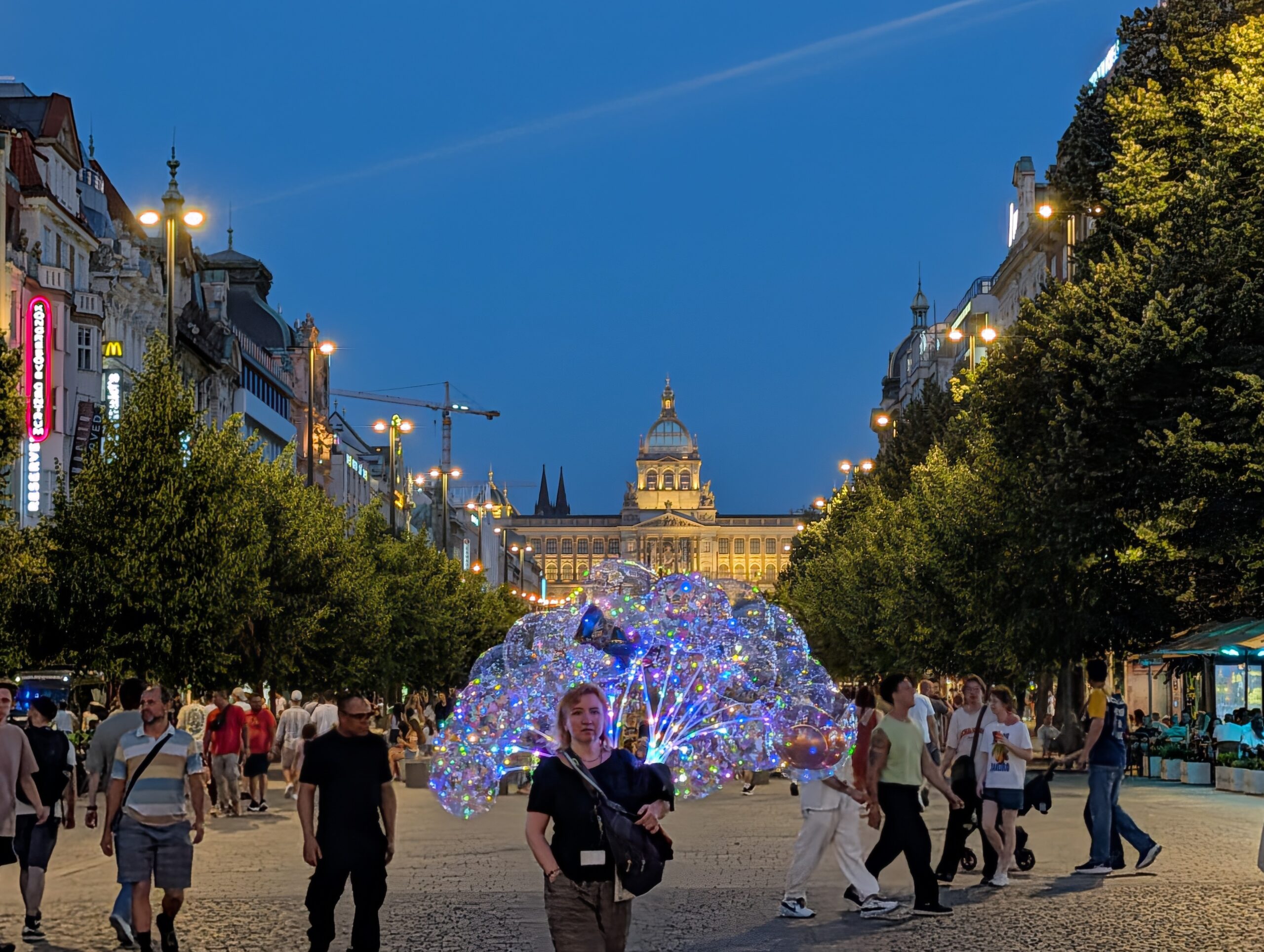 Blick über den Wenzelsplatz auf das beleuchtete Nationalmuseum in Prag bei Abenddämmerung.