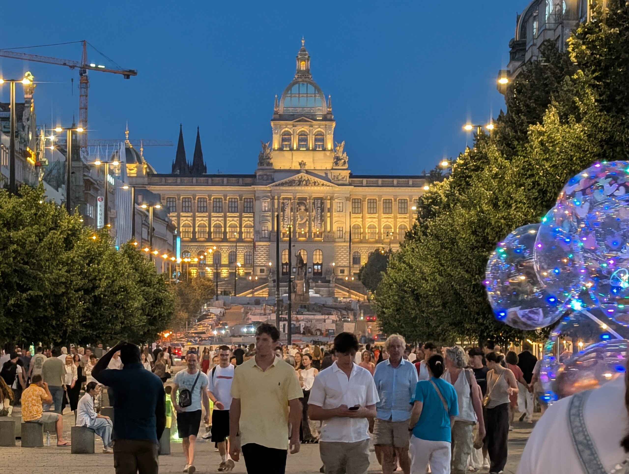 Blick über den Wenzelsplatz auf das beleuchtete Nationalmuseum in Prag bei Abenddämmerung.