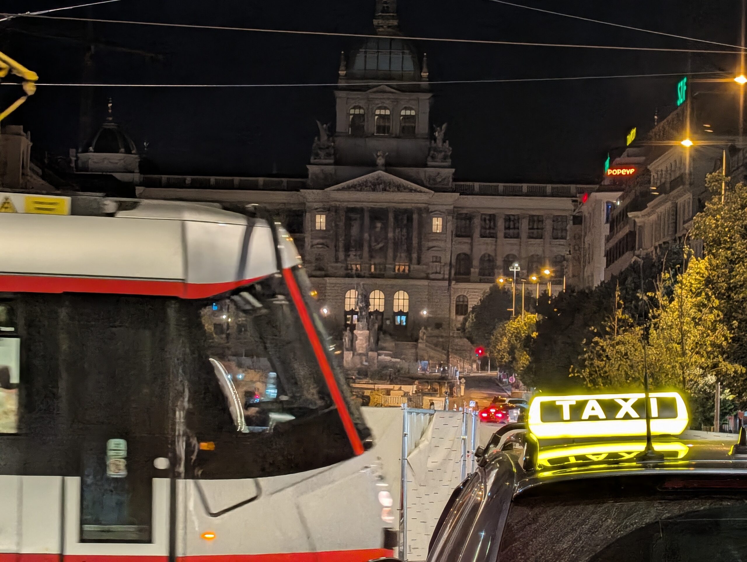Straßenbahn und Taxi vor dem Nationalmuseum am Wenzelsplatz in Prag bei Nacht.