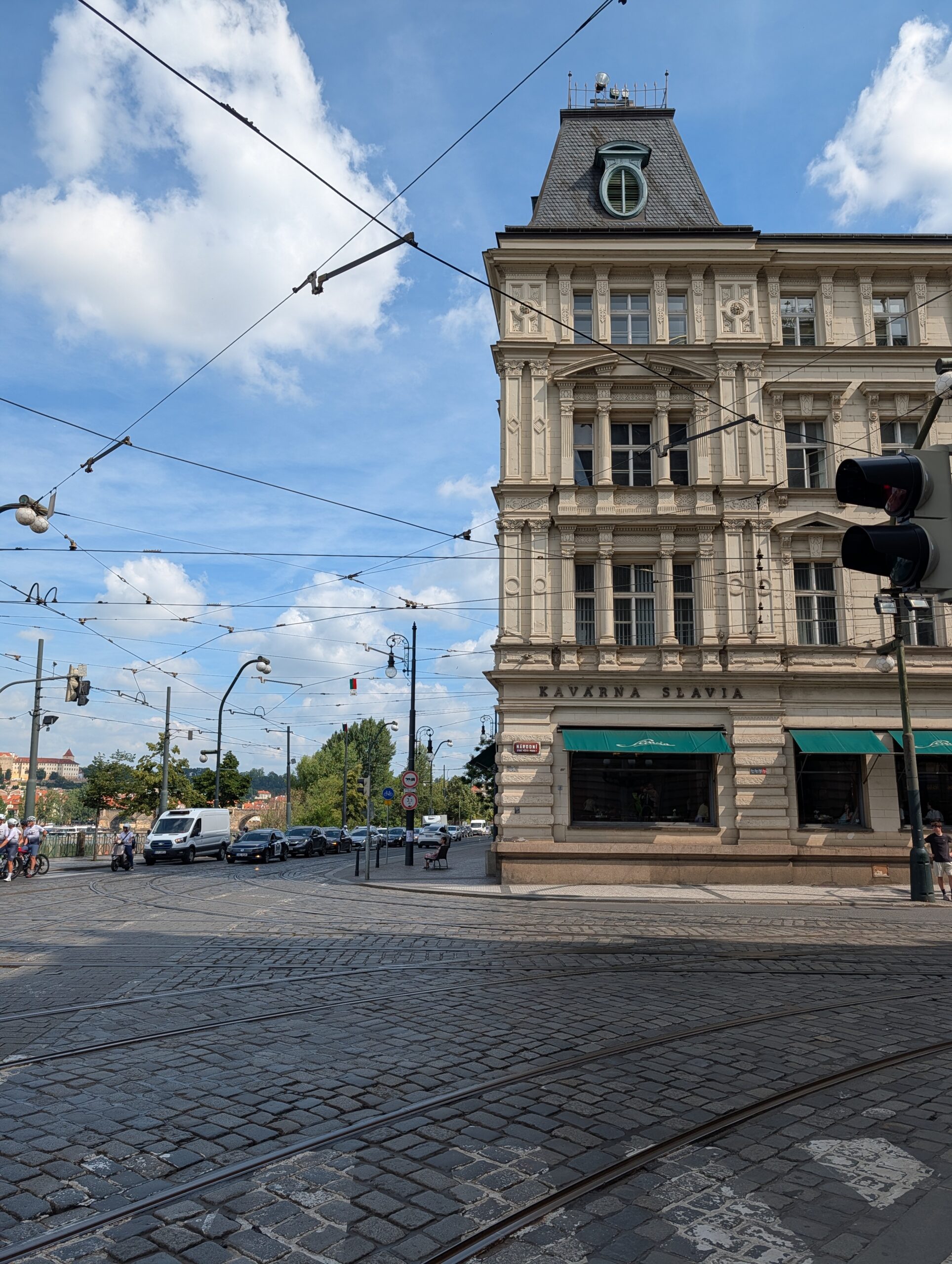 Café Slavia in einem historischen Eckgebäude in Prag mit Straßenbahngleisen und Oberleitungen