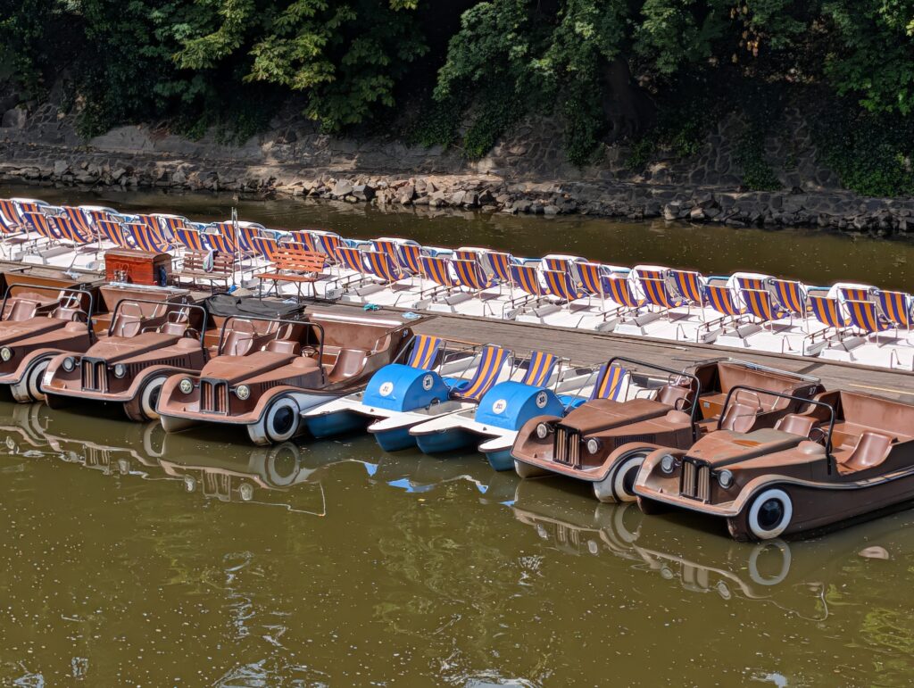 Braune und blau-weiße Tretboote an einem Steg in Prag