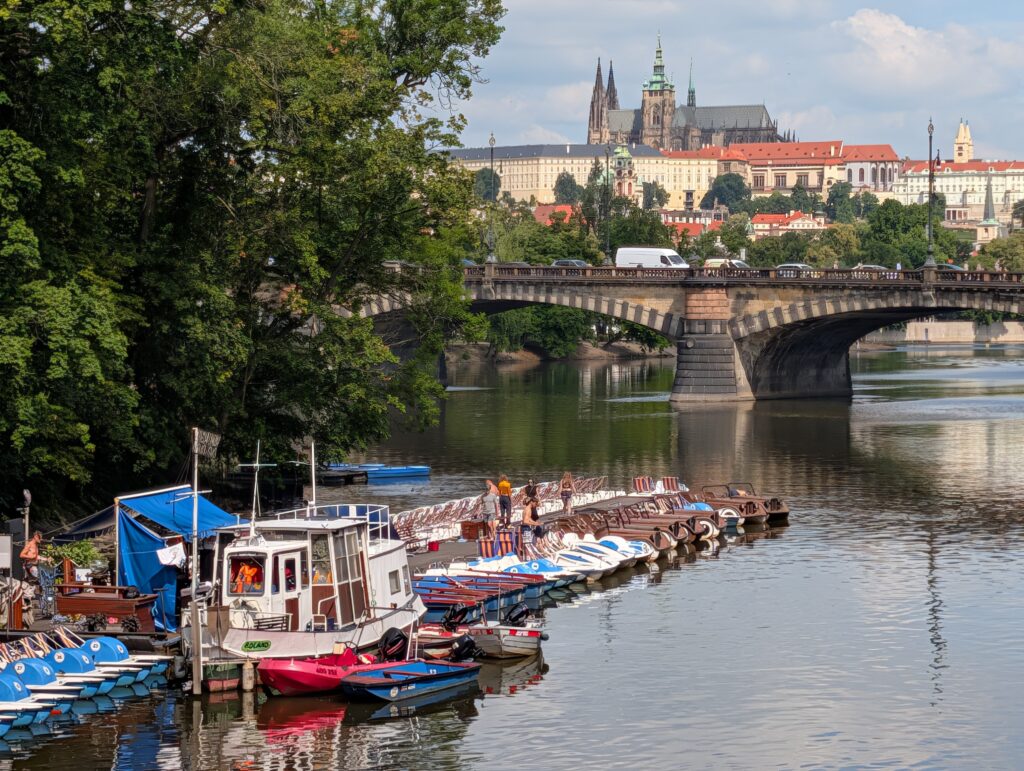 Tretboote an der Moldau mit Brücke, Prager Burg und Veitsdom im Hintergrund